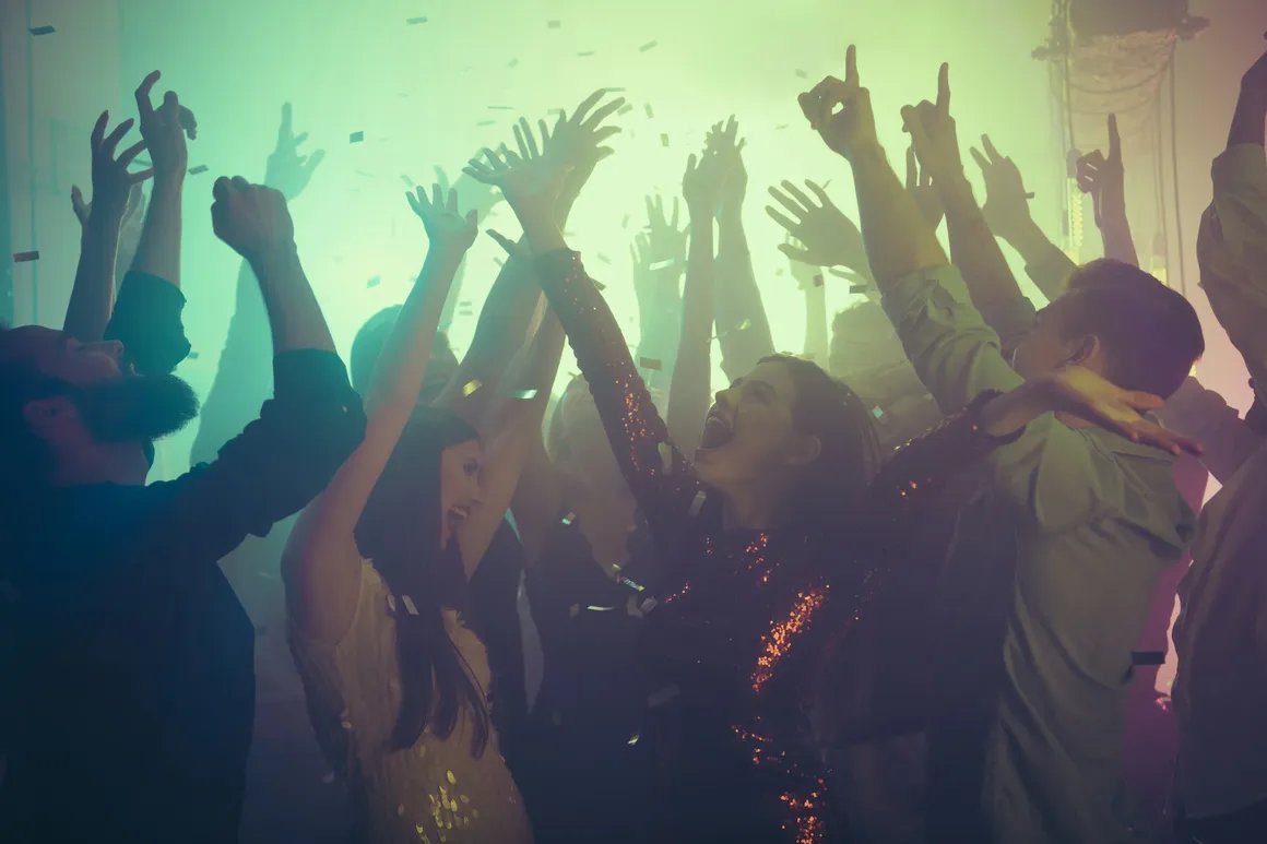 Crowd with hands up under stage lighting